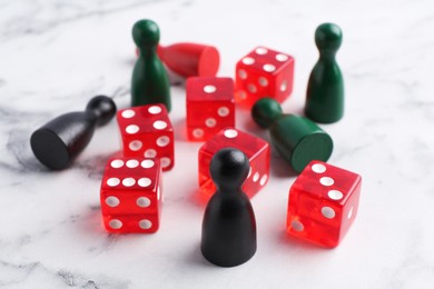 Photo of Red dices and color game pieces on white marble table, closeup