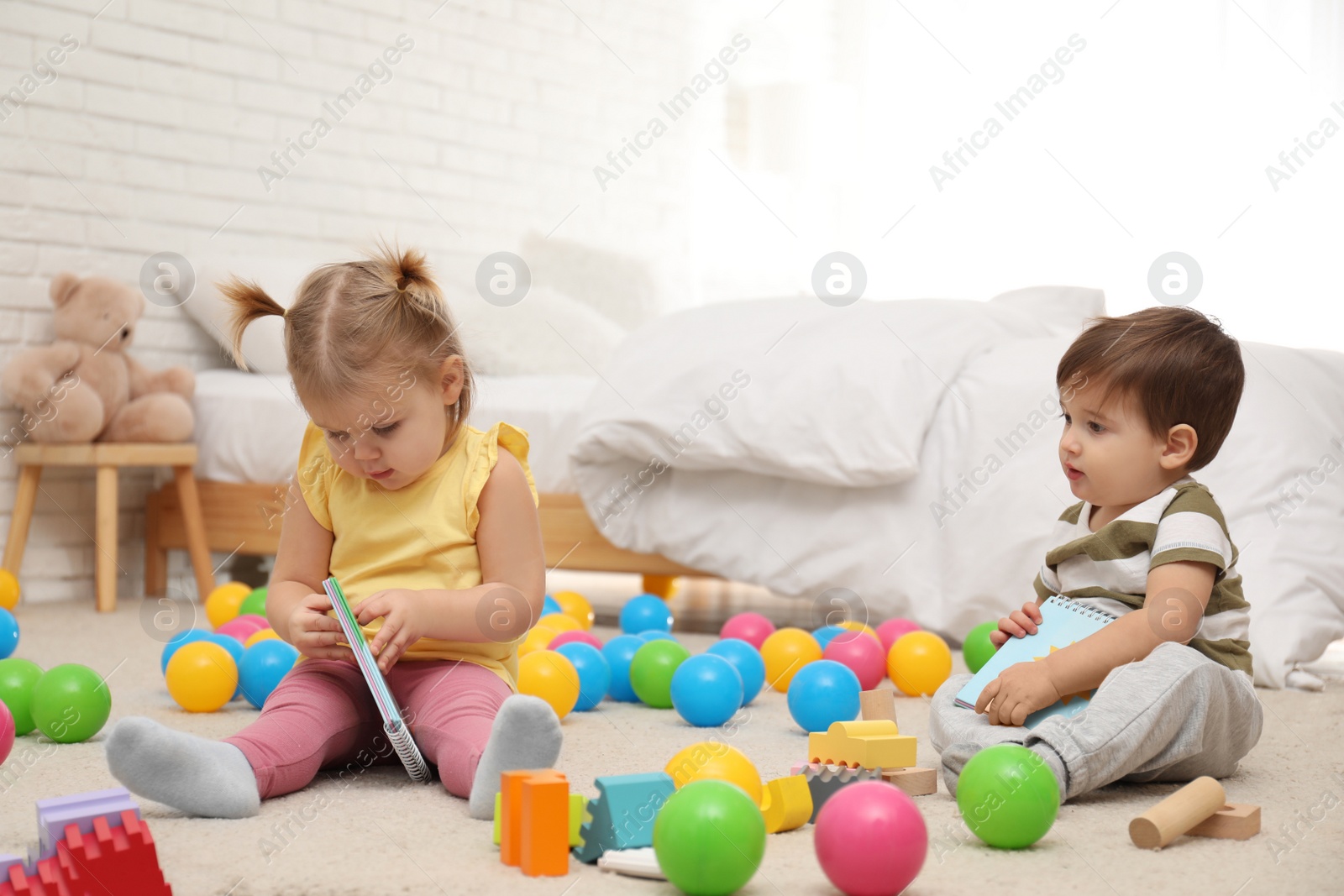 Photo of Cute little children playing with toys on floor at home