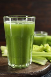 Glasses of delicious celery juice and vegetables on wooden board