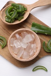 Photo of Aloe vera gel and slices of plant on white wooden table, top view