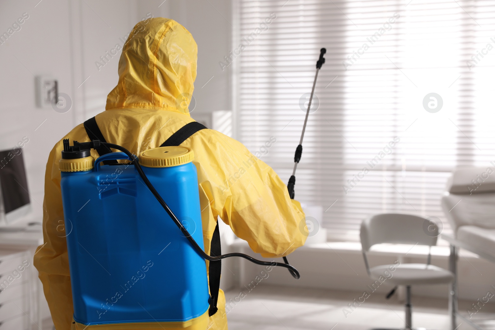 Photo of Man in protective suit sanitizing doctor's office. Medical disinfection