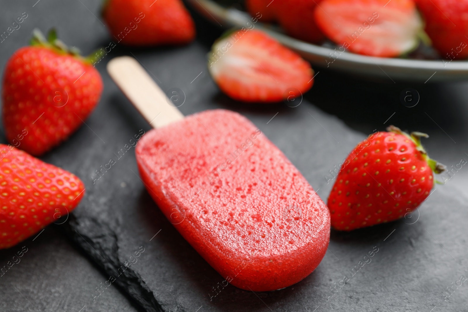 Photo of Tasty strawberry ice pop on dark table, closeup. Fruit popsicle