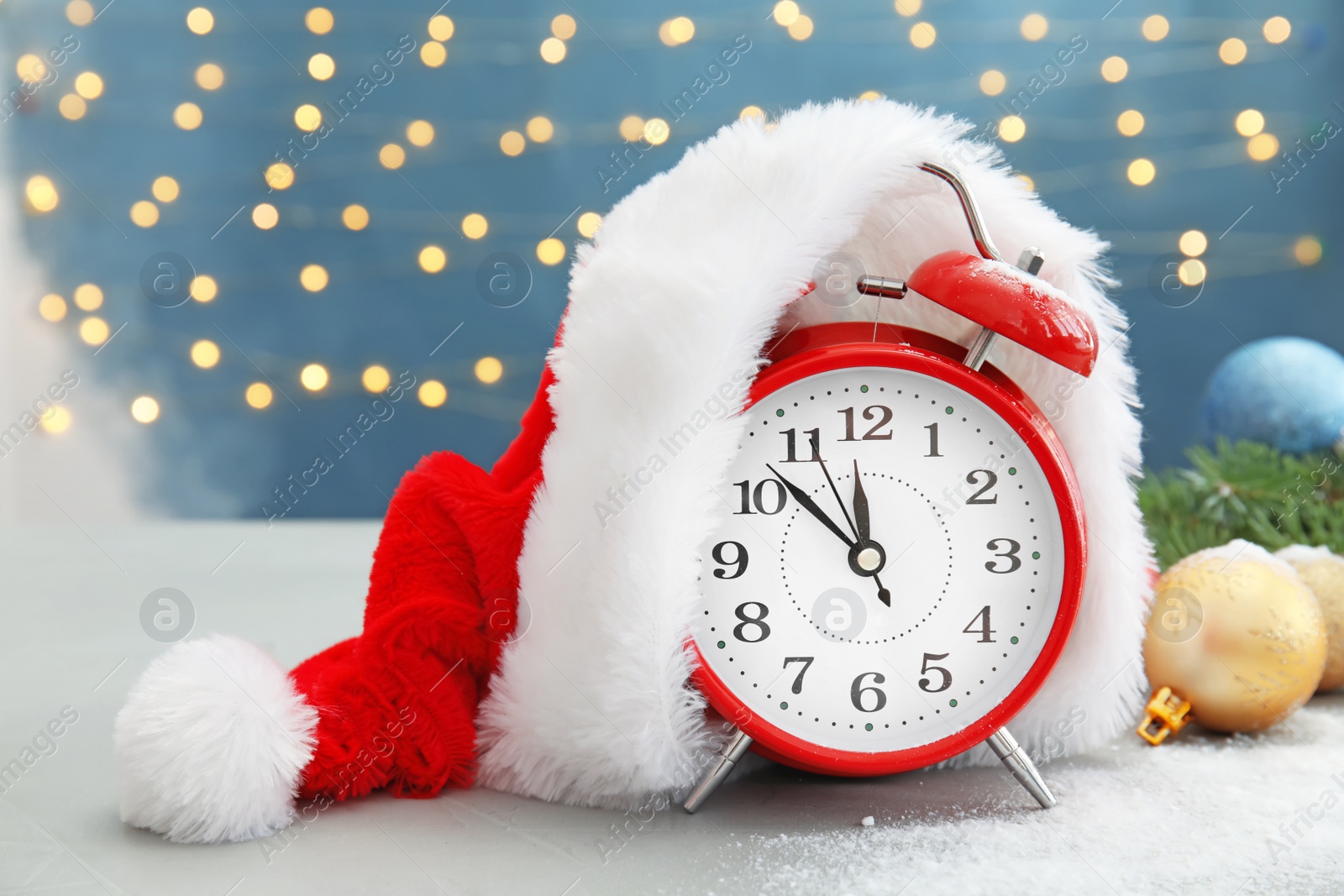 Photo of Alarm clock with Santa hat and festive decor on table. Christmas countdown