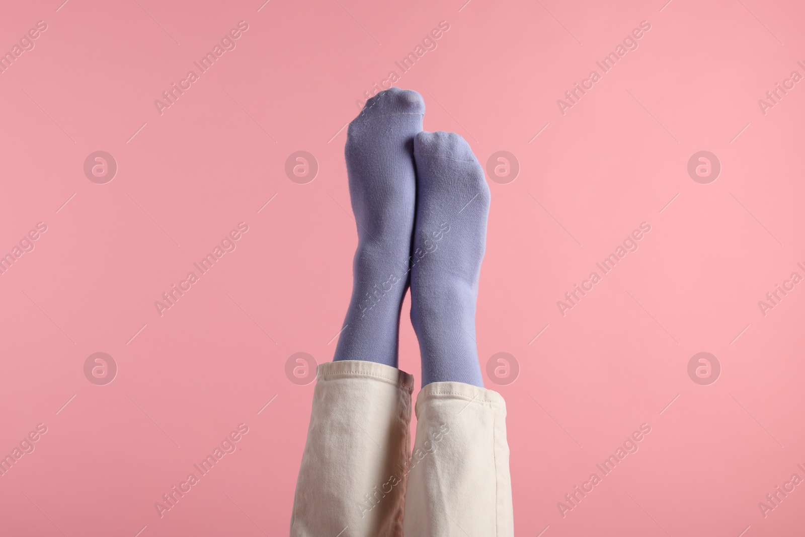 Photo of Woman in stylish purple socks and pants on pink background, closeup