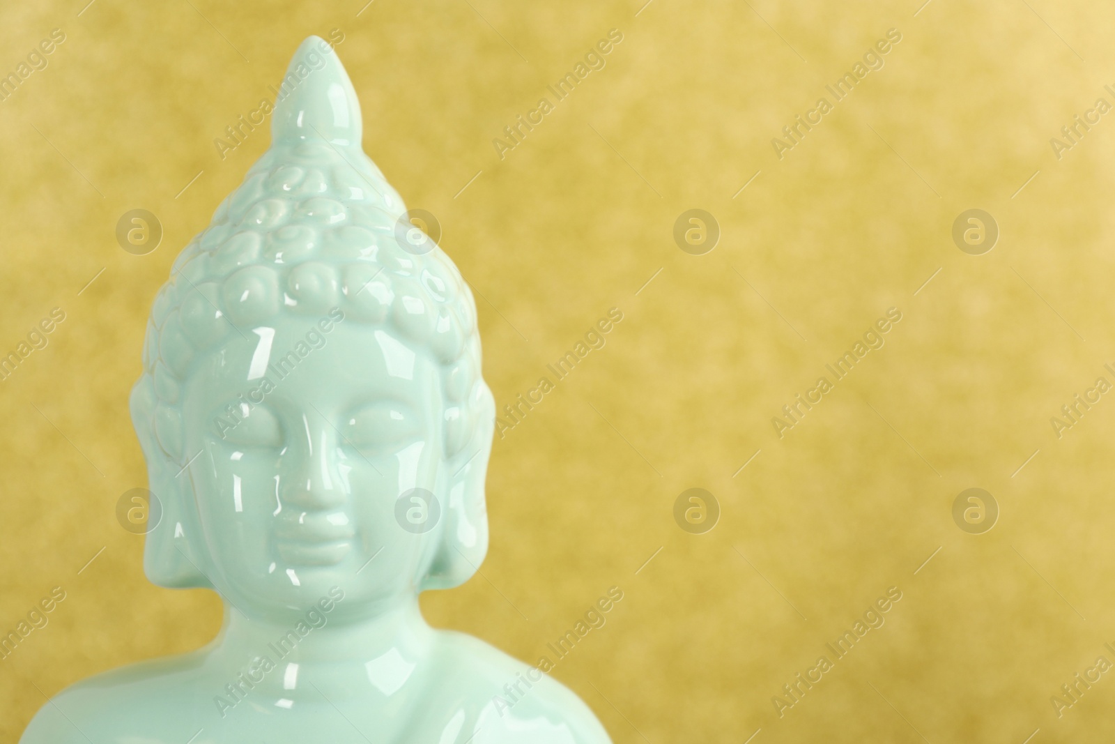 Photo of Buddha statue on golden background, closeup. Space for text