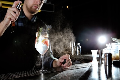 Photo of Barman making grapefruit gin tonic cocktail at counter in pub, closeup. Space for text