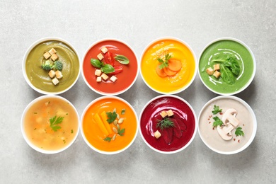 Photo of Various cream soups in bowls on grey background, top view