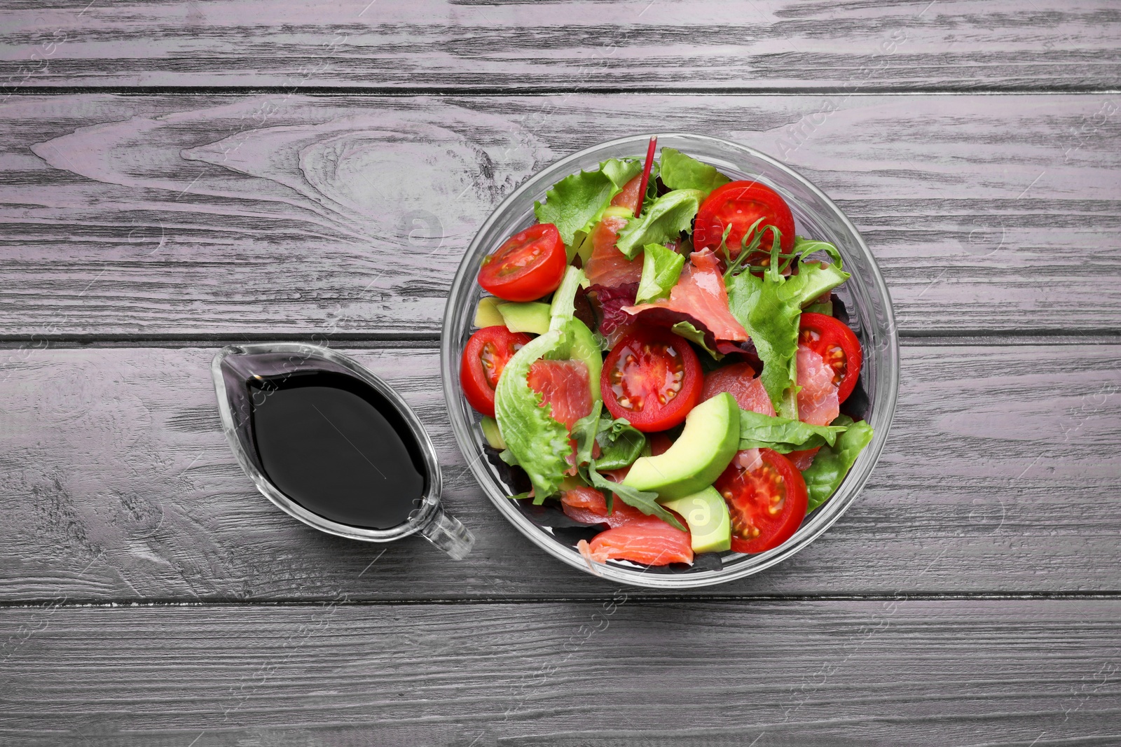 Photo of Tasty soy sauce and bowl with salad on wooden table, flat lay