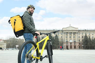 Courier with thermo bag and bicycle on city street. Food delivery service