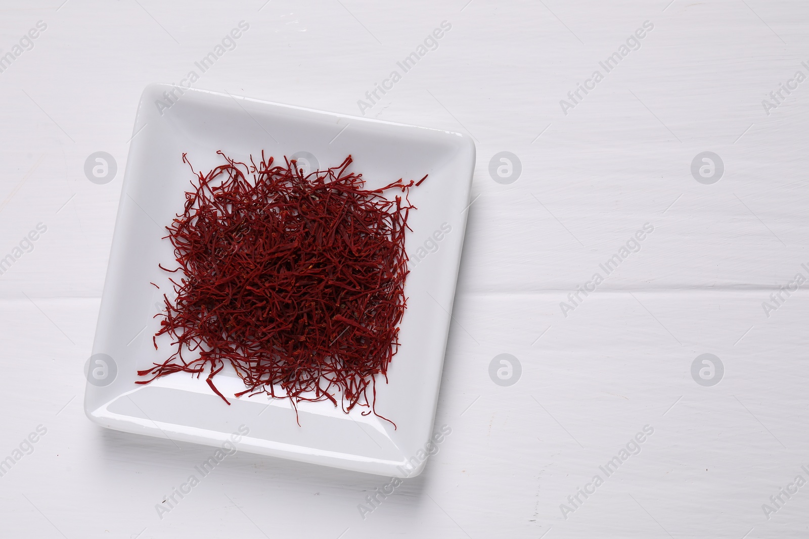 Photo of Aromatic saffron on white wooden table, top view. Space for text