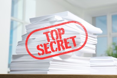 Image of Top Secret stamp. Stacked sheets of paper on table indoors