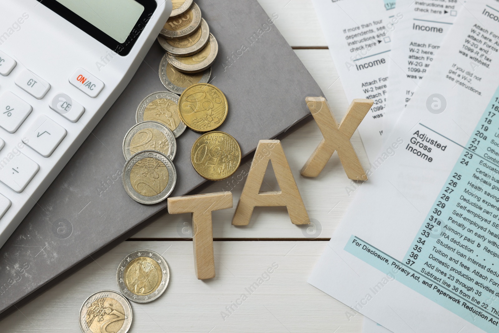 Photo of Word Tax made of letters, calculator, notebook, documents and coins on white wooden table, flat lay