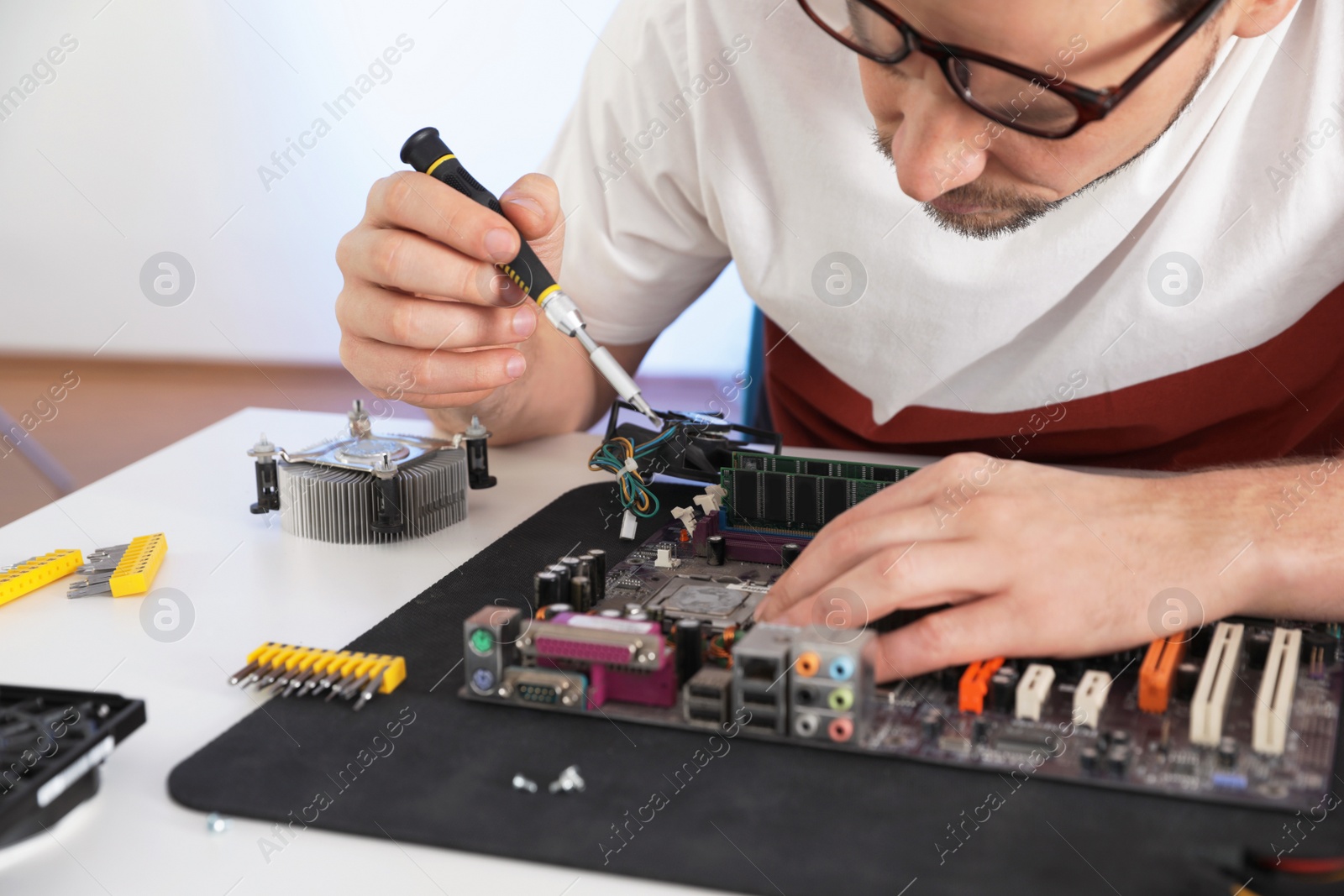 Photo of Male technician repairing motherboard at table, closeup