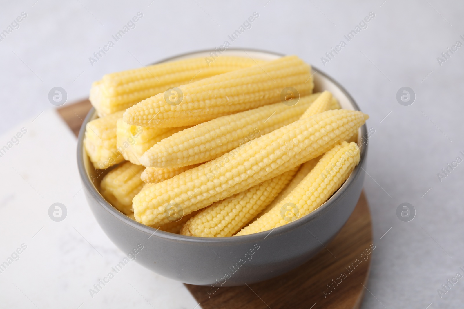 Photo of Tasty fresh yellow baby corn in bowl on white table