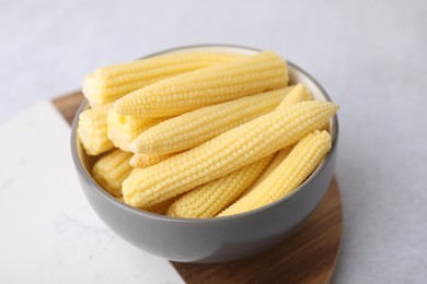 Tasty fresh yellow baby corn in bowl on white table