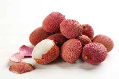 Photo of Pile of fresh ripe lychees on white wooden table, closeup