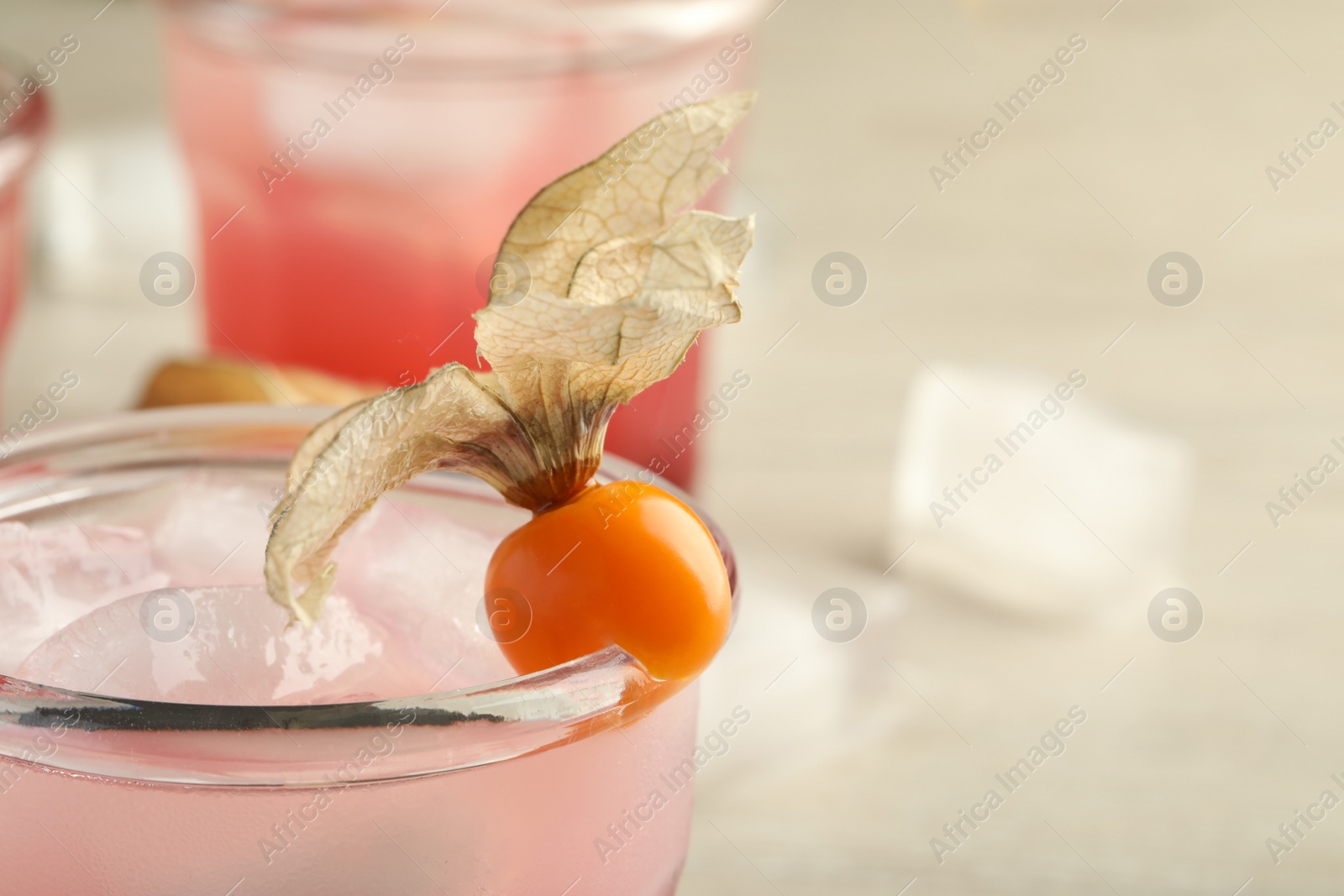 Photo of Refreshing cocktail decorated with physalis fruit on blurred background, closeup. Space for text