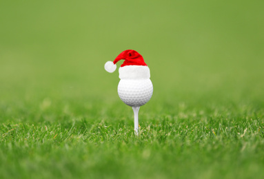 Image of Golf ball with small Santa hat on tee at course