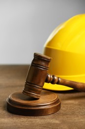 Photo of Construction and land law concepts. Gavel and hard hat on wooden table