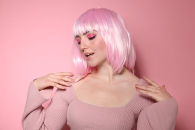 Photo of Beautiful woman with bright makeup and fake freckles on pink background