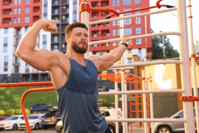 Photo of Man showing biceps at outdoor gym on sunny day