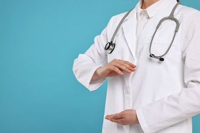 Photo of Doctor with stethoscope holding something on light blue background, closeup. Space for text
