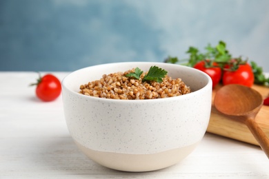 Bowl of buckwheat porridge with parsley on white table