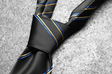 One striped necktie on grey textured background, closeup
