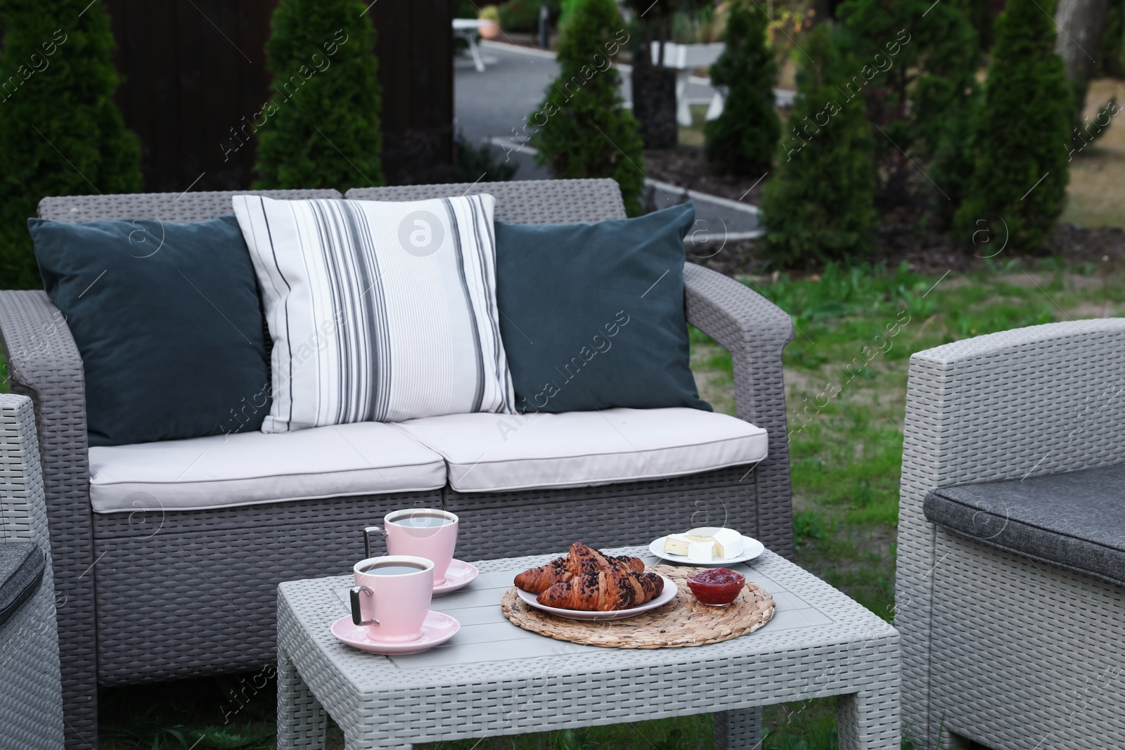 Photo of Outdoor breakfast with tea and croissants on rattan table in garden