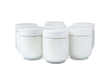 Glass jars with delicious homemade yogurt on white background