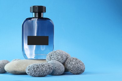 Photo of Stylish presentation of luxury men`s perfume on stones against light blue background. Space for text