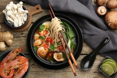 Photo of Flat lay composition with delicious ramen in bowl and ingredients on wooden table. Noodle soup