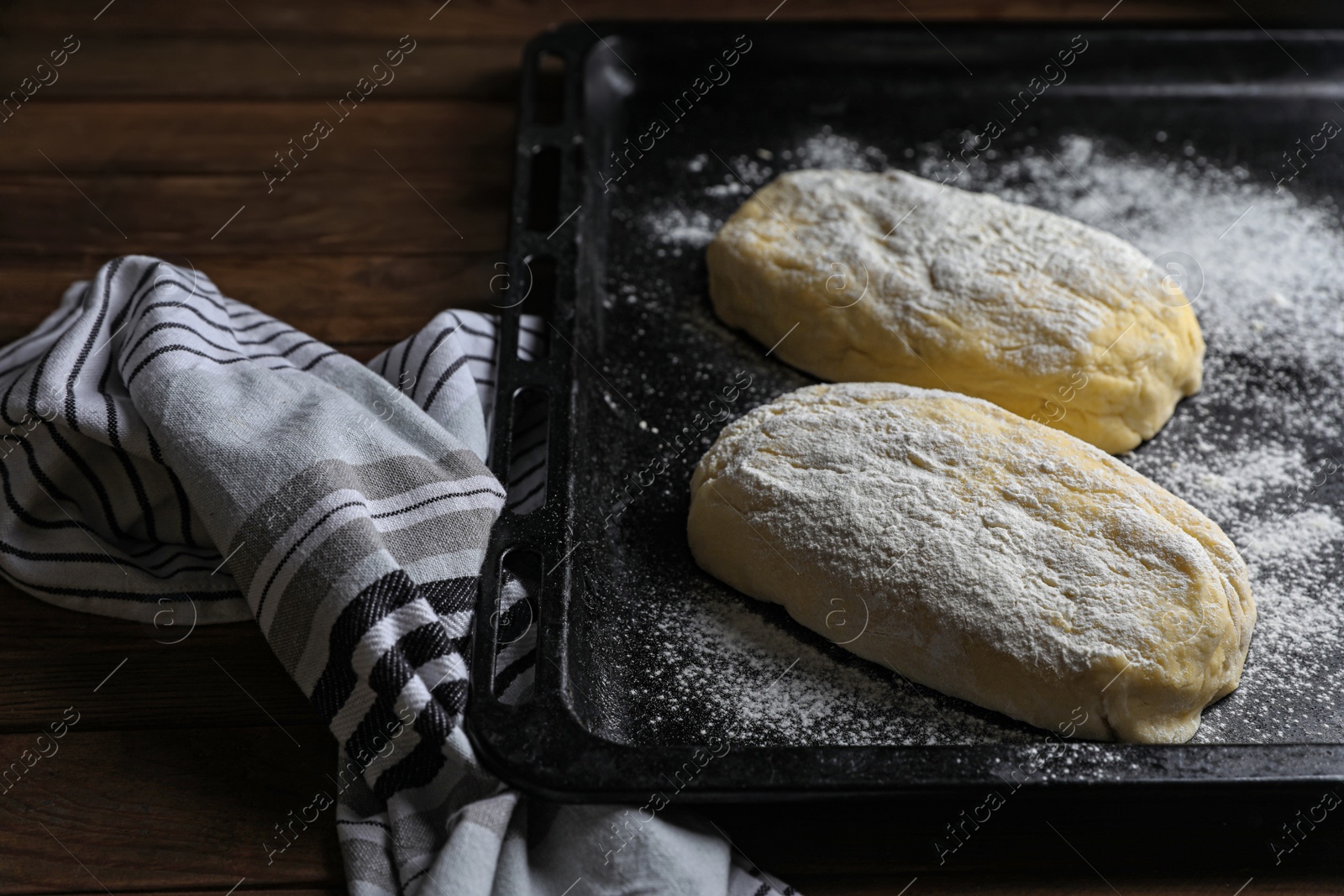 Photo of Raw dough for ciabatta and flour on wooden table