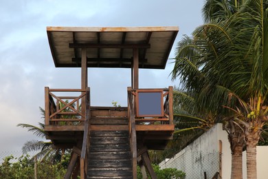 Photo of Wooden lifeguard tower near palm trees on sunny day
