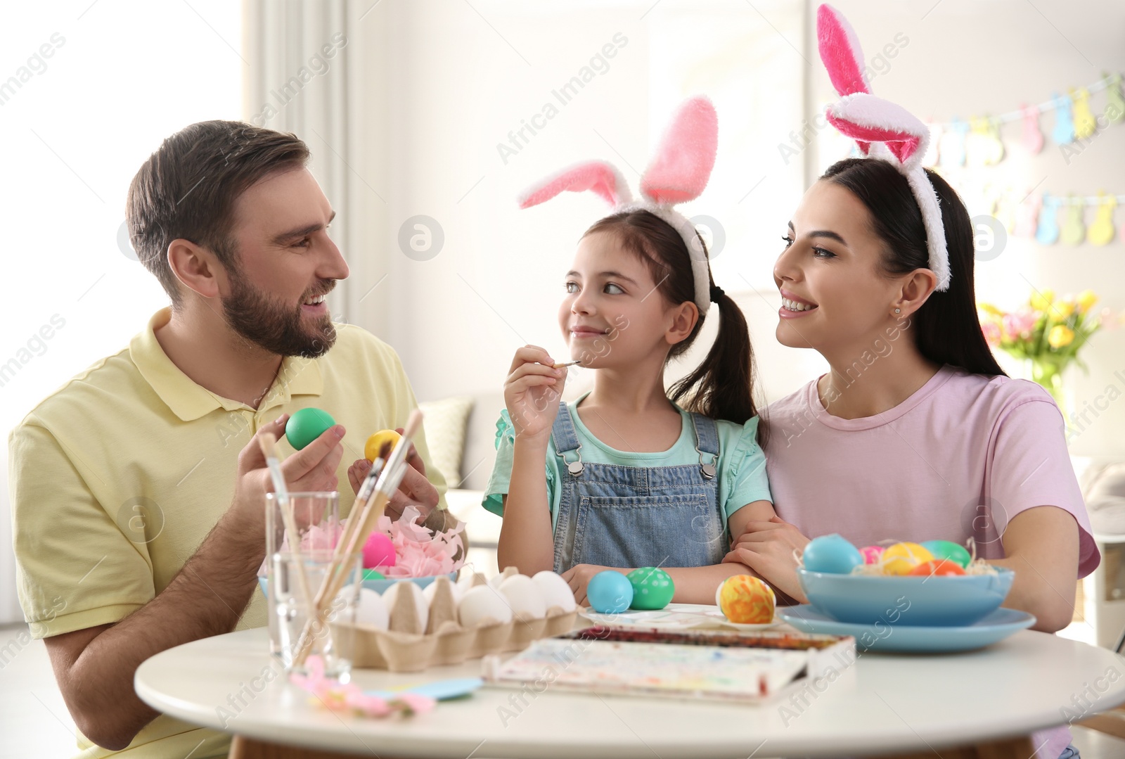 Photo of Happy family painting Easter eggs at table indoors