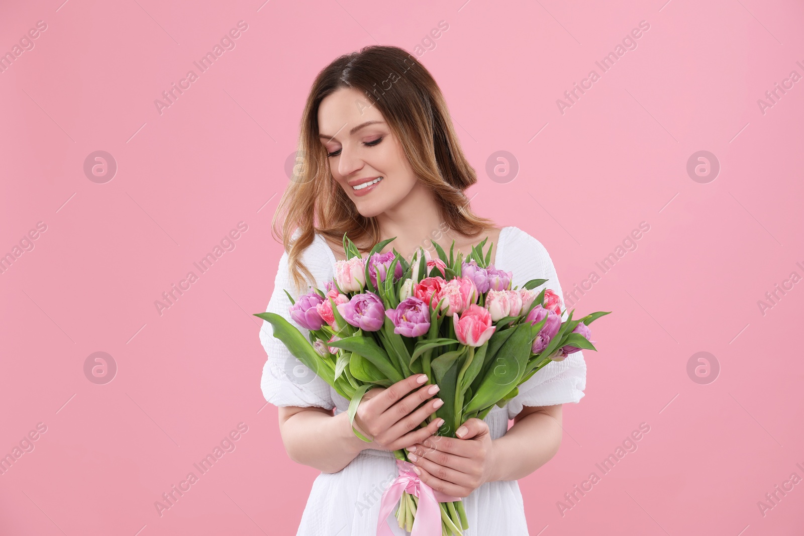 Photo of Happy young woman with bouquet of beautiful tulips on pink background