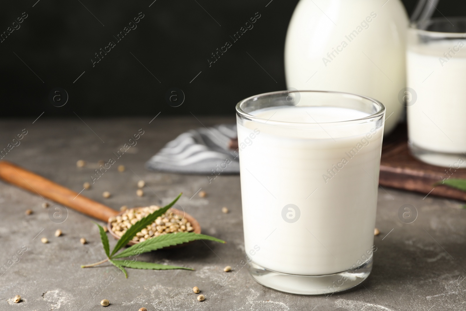 Photo of Composition with glass of hemp milk on grey table against black background. Space for text
