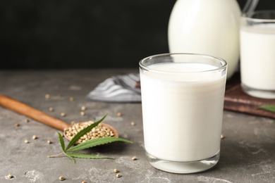 Composition with glass of hemp milk on grey table against black background. Space for text