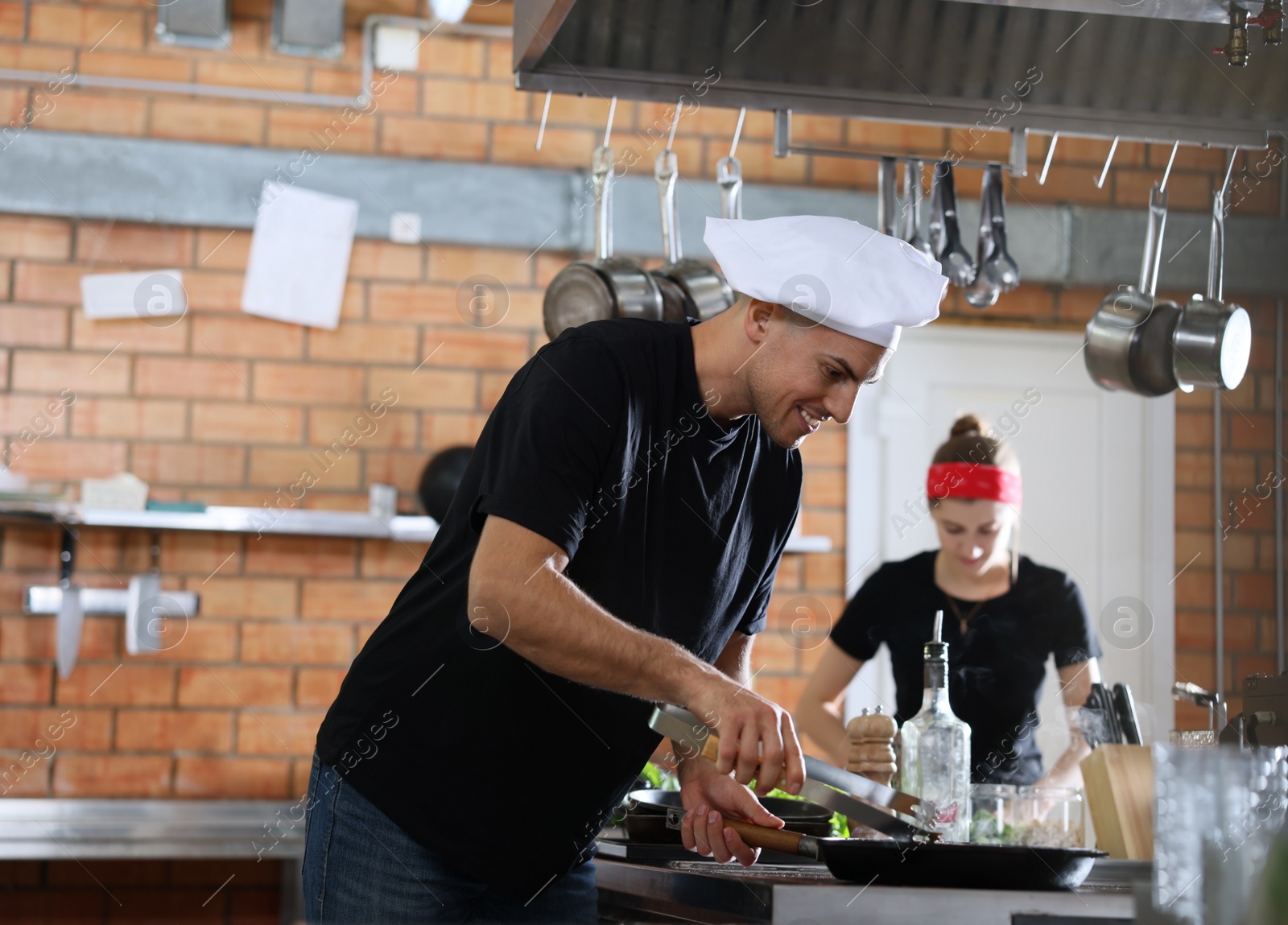 Photo of Professional chef cooking food on stove in restaurant kitchen