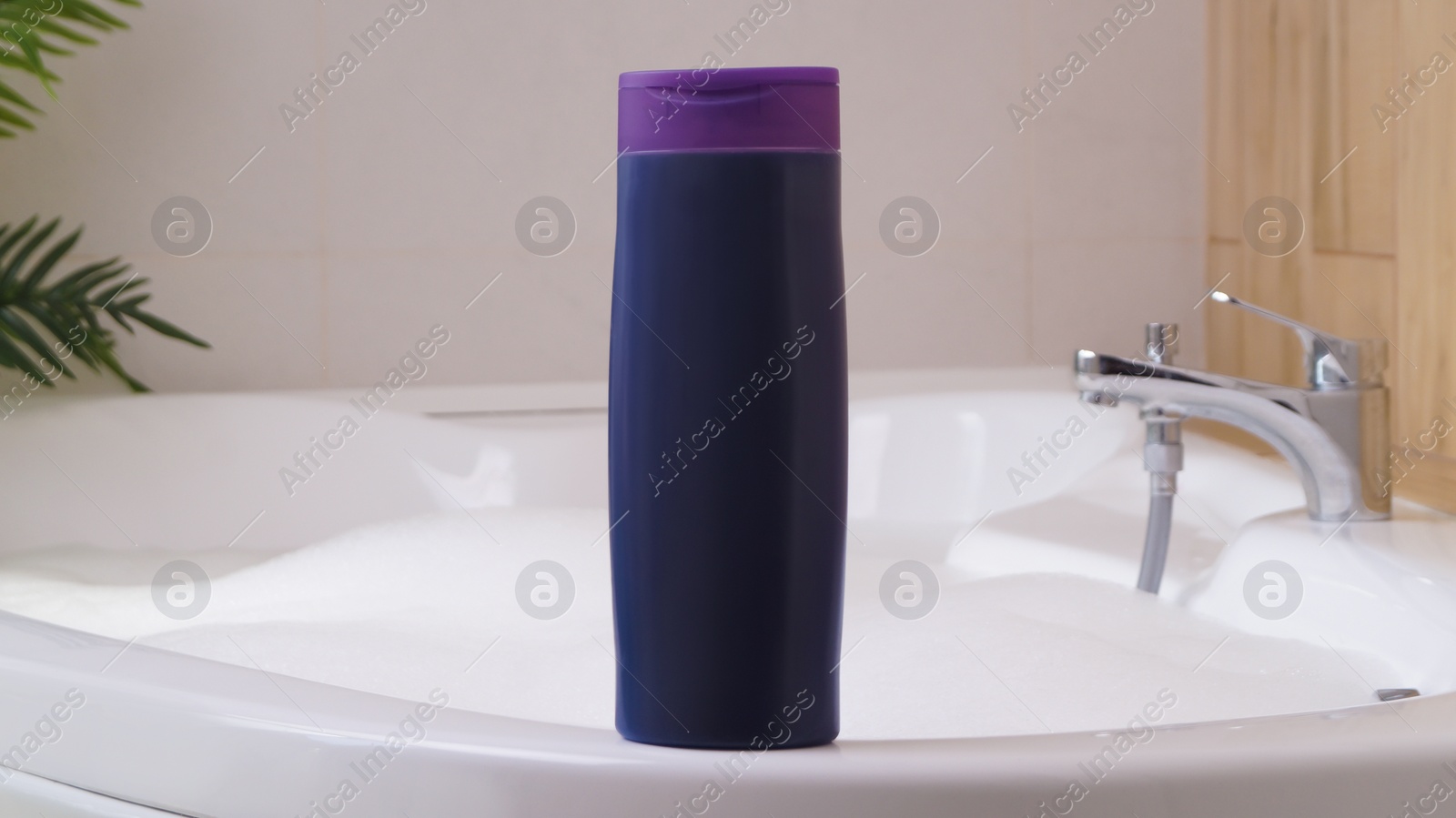 Photo of Purple bottle of bubble bath on tub indoors