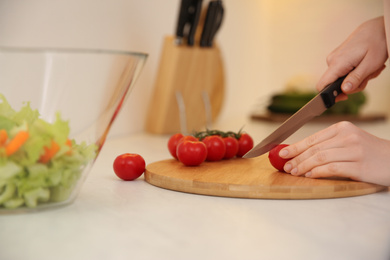 Young woman cooking at table in kitchen, closeup