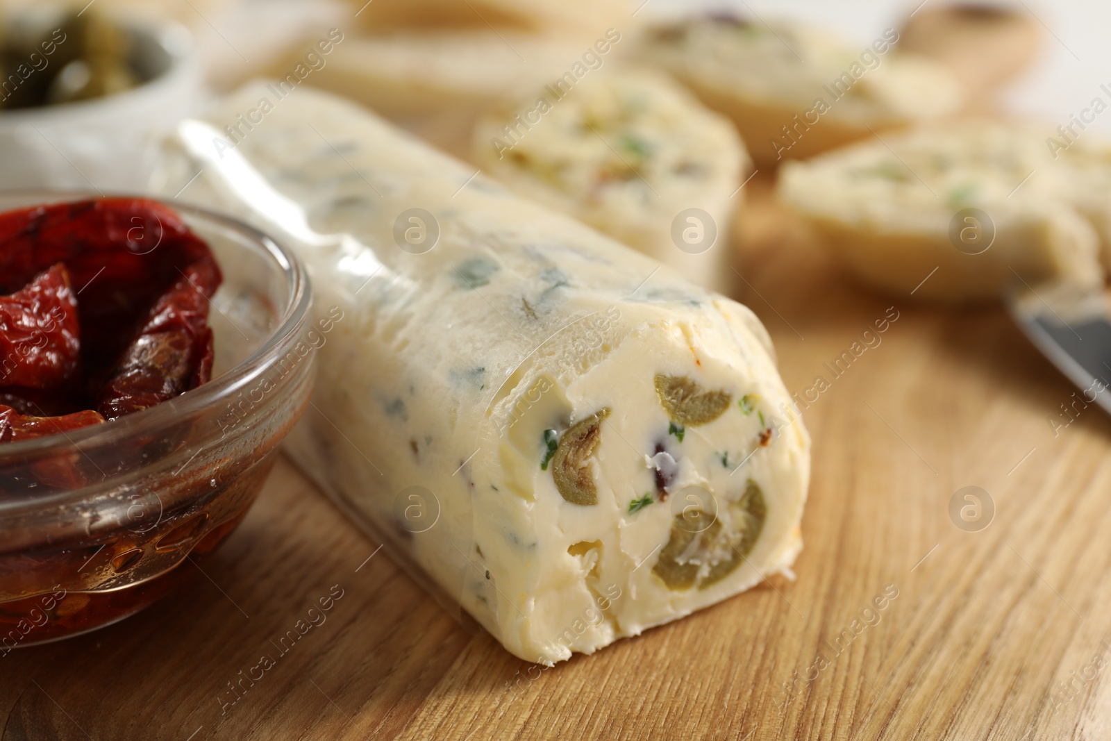 Photo of Tasty butter with olives, green onion and chili pepper on wooden table, closeup