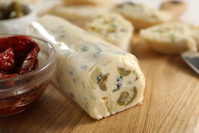 Photo of Tasty butter with olives, green onion and chili pepper on wooden table, closeup