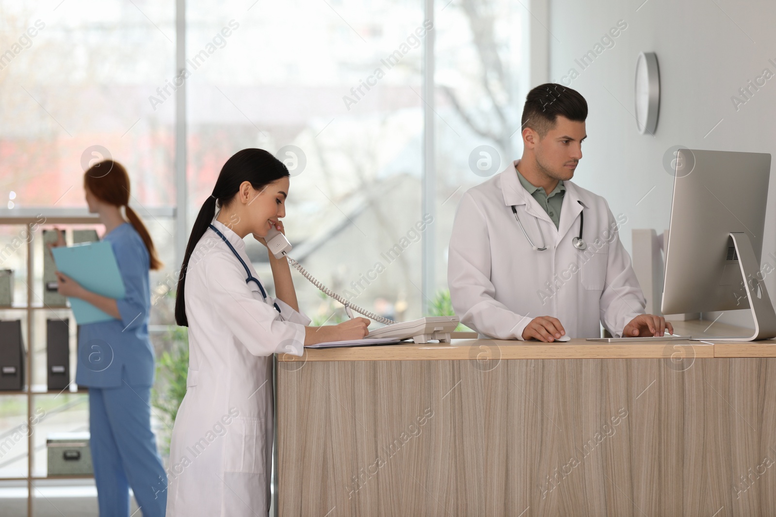 Photo of Receptionist and doctor working at countertop in hospital