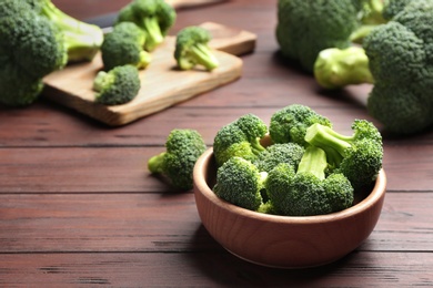 Photo of Bowl of fresh green broccoli on wooden table, space for text