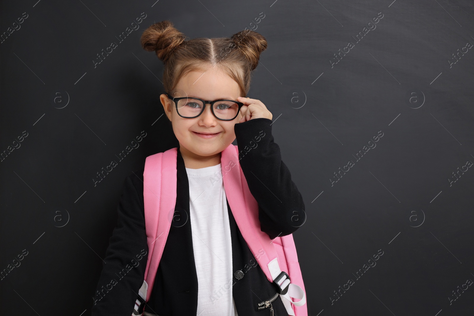 Photo of Happy little school child with backpack near chalkboard