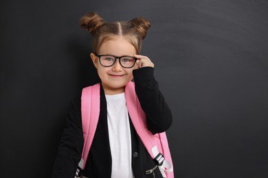 Photo of Happy little school child with backpack near chalkboard