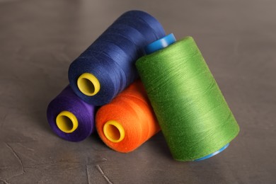 Photo of Set of color sewing threads on grey table, closeup