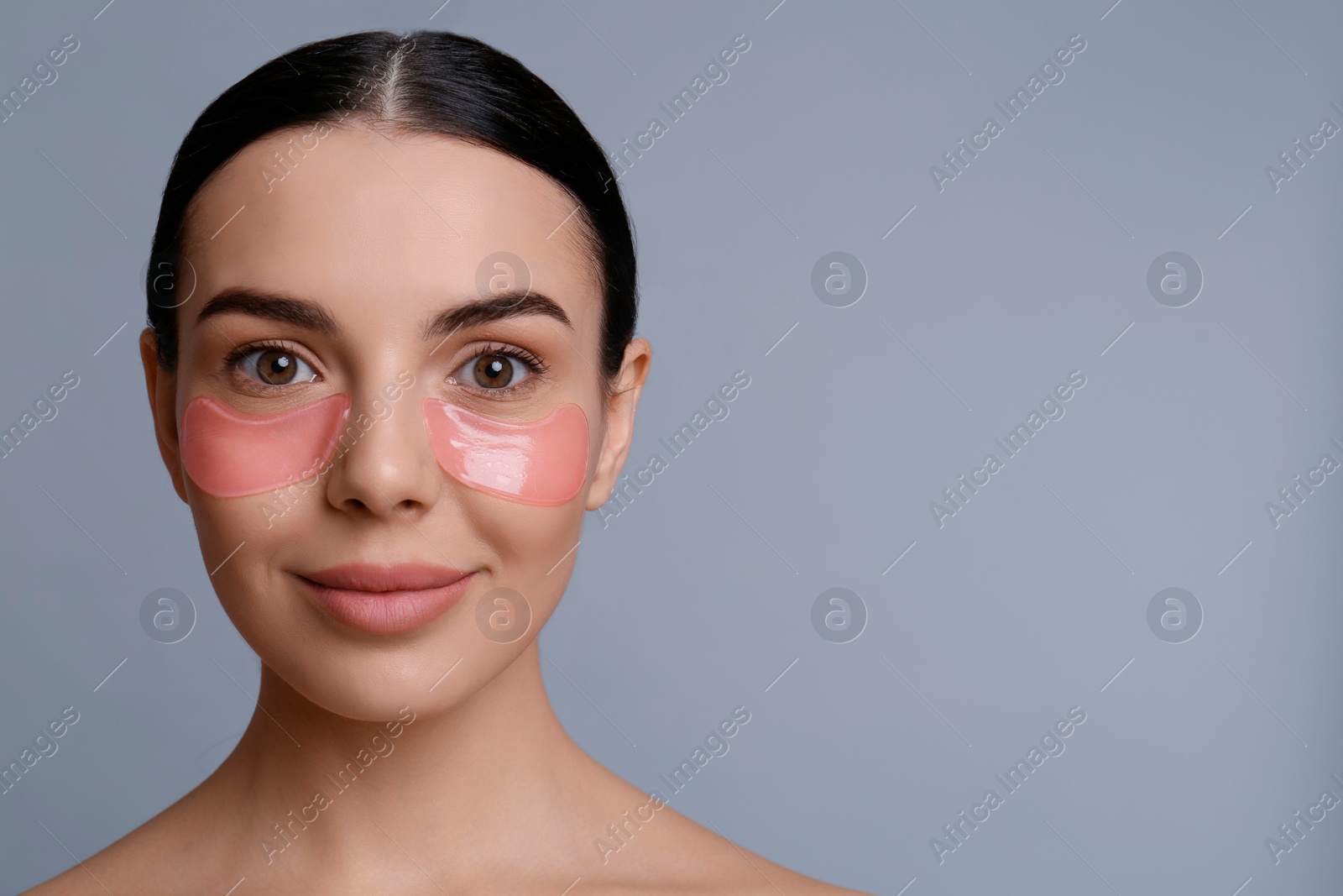 Photo of Beautiful young woman with under eye patches on grey background, space for text