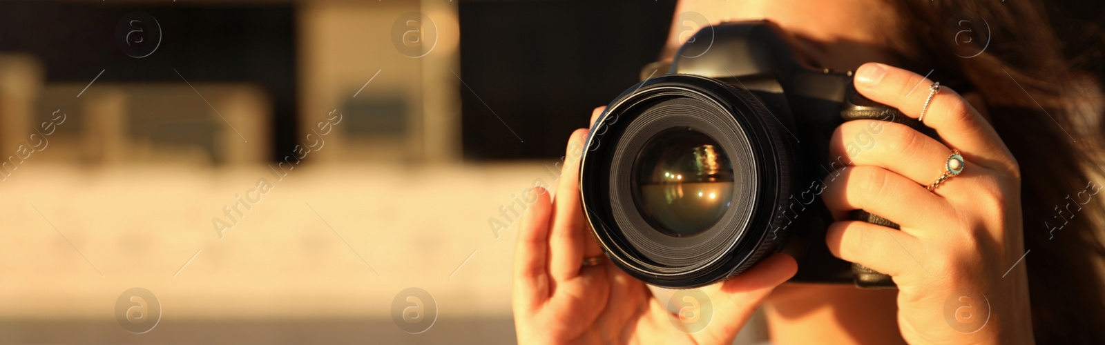 Image of Young photographer taking picture with professional camera outdoors, space for text. Banner design